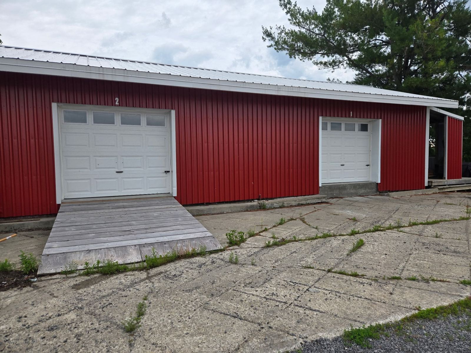 Red barn-style garage building with white overhead doors, suitable for covered boat storage at Osgoode Storage.