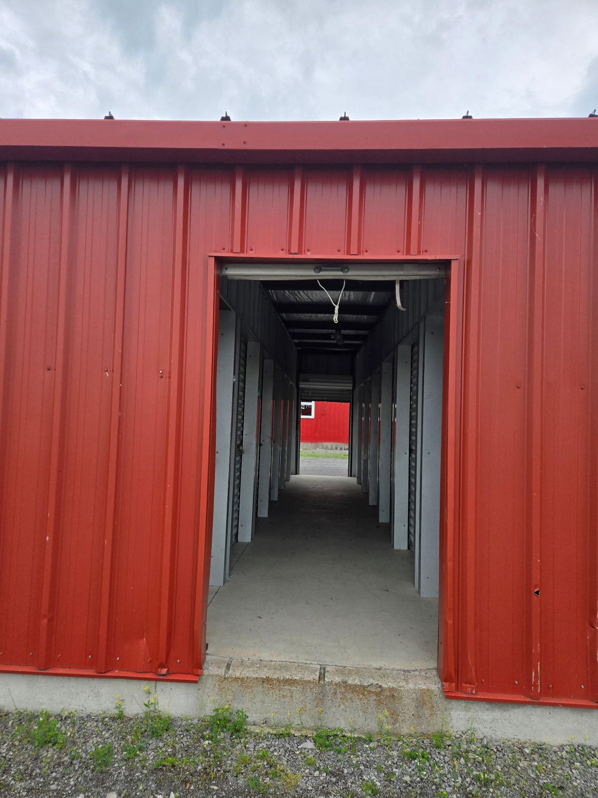 Covered hallway between red storage unit doors at Osgoode Storage, showing enclosed temperature-controlled storage space.