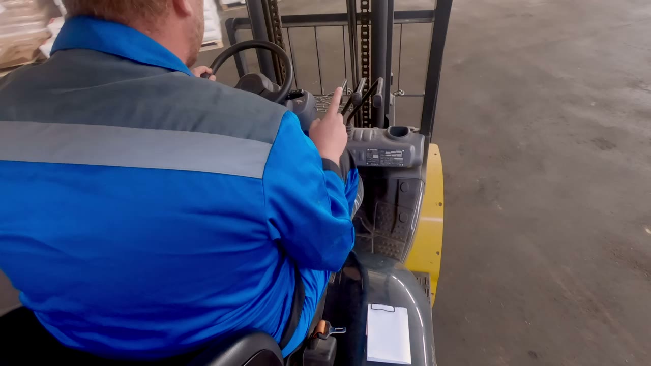 A forklift operator moving palletized inventory inside a large indoor storage facility.